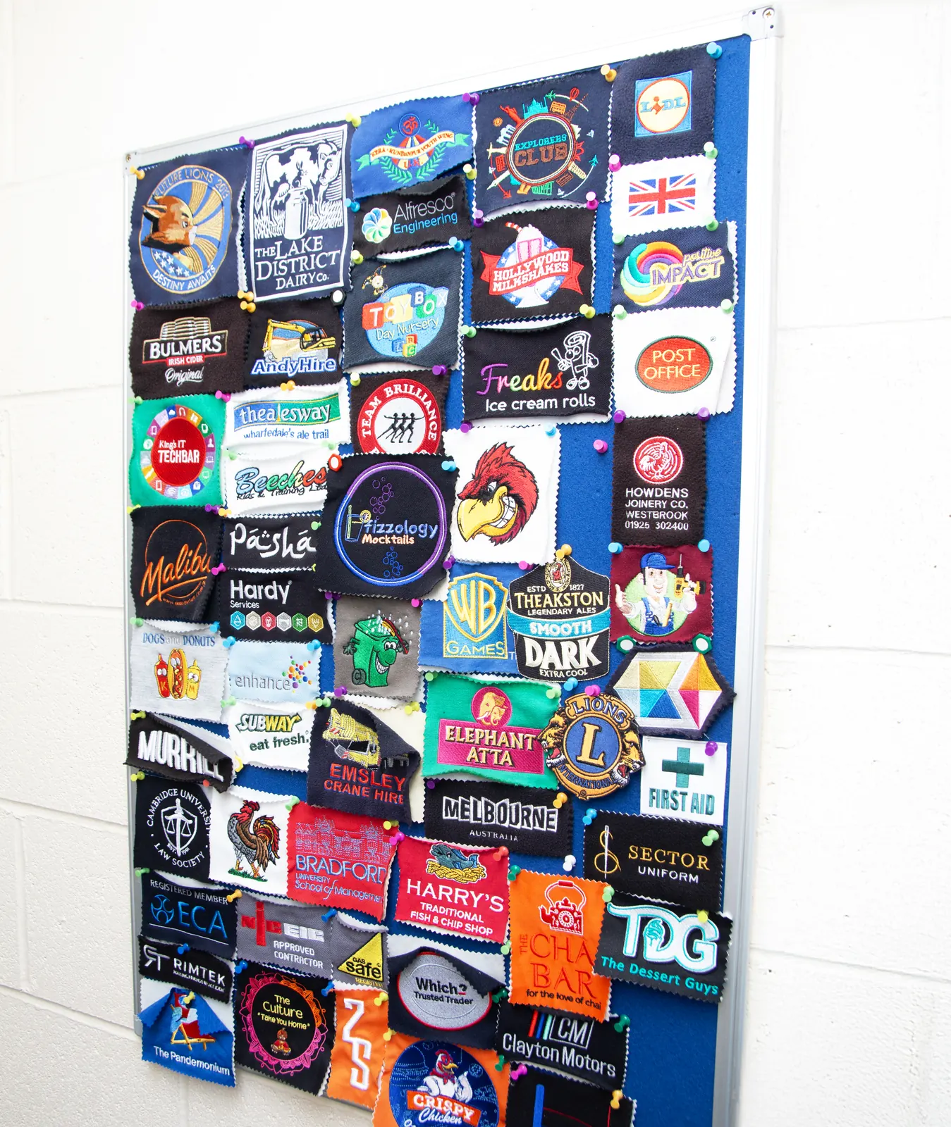 Customer logo patches pinned to the sample board at BR Apparel