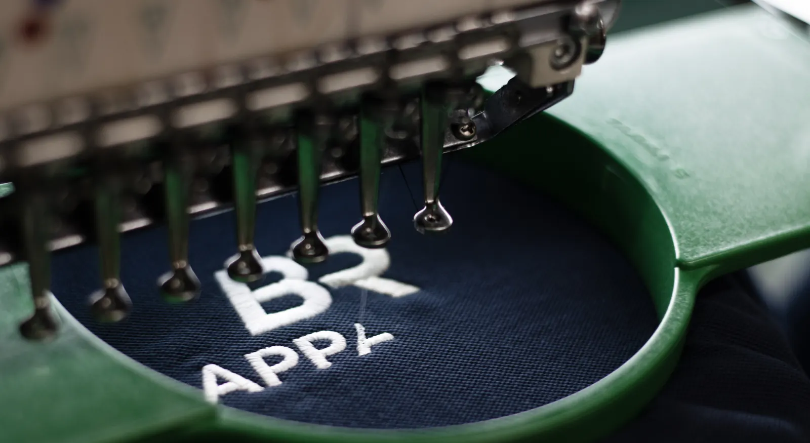 Close-up of a logo being embroidered onto a navy polo shirt