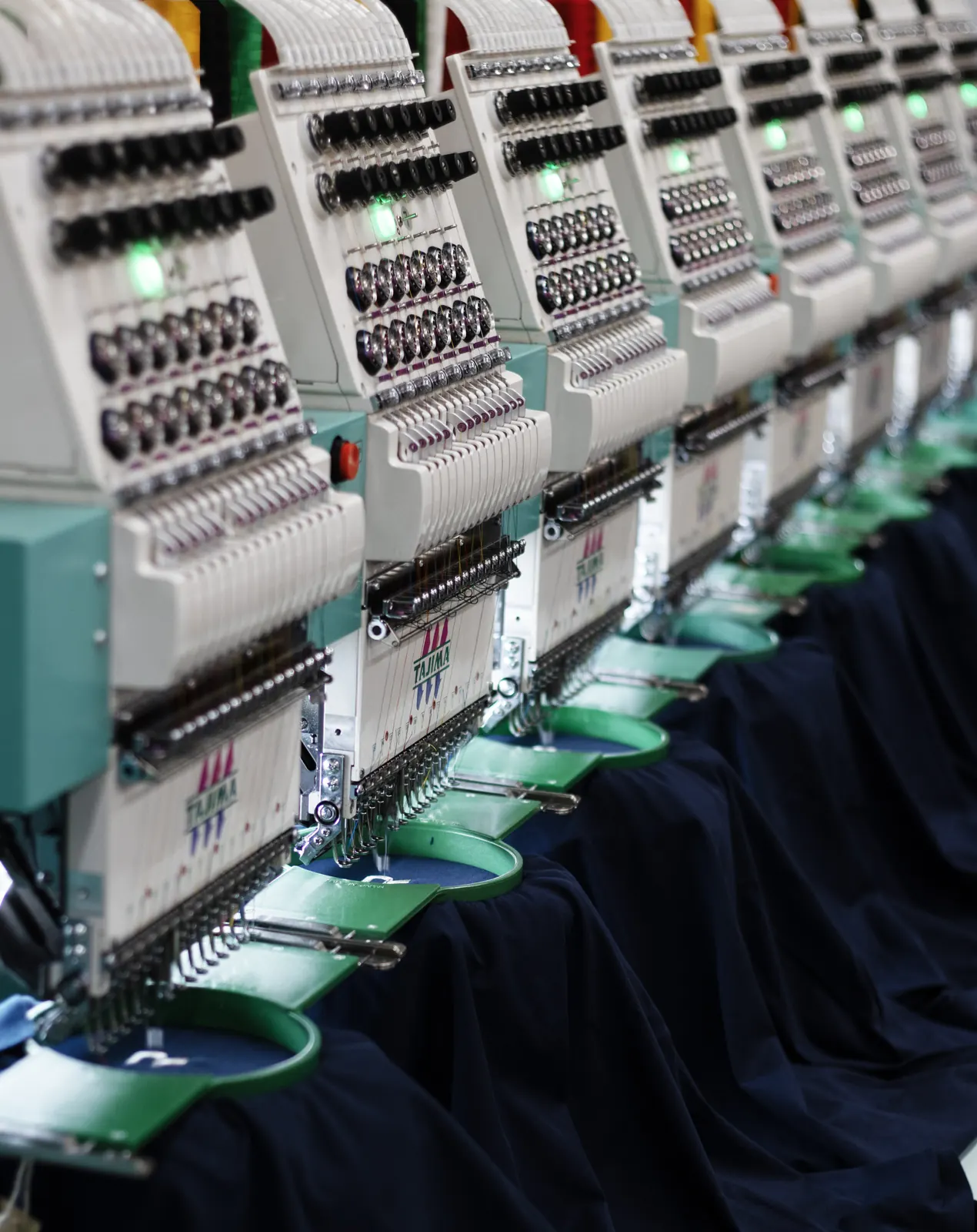 Rows of navy workwear on the embroidery machine line at BR Apparel in Bradford
