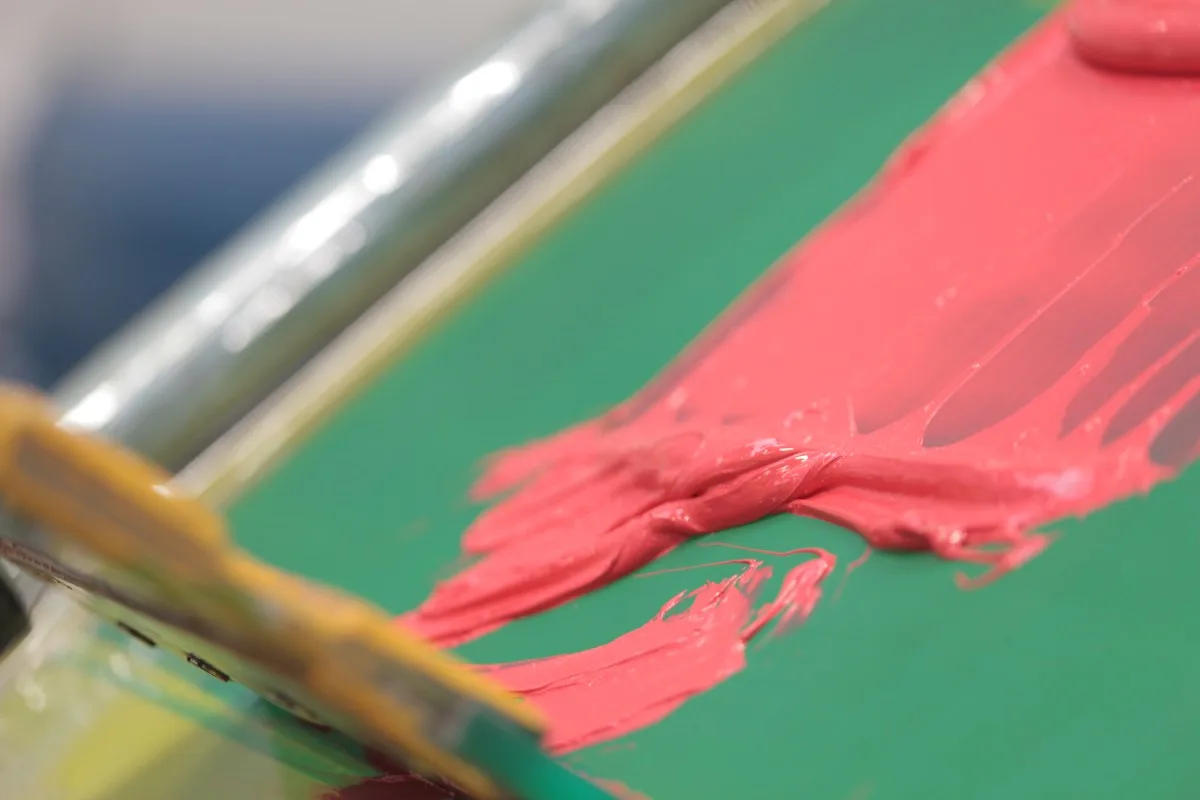 Spot-colour plastisol ink and squeegee on a screen ready for a print run